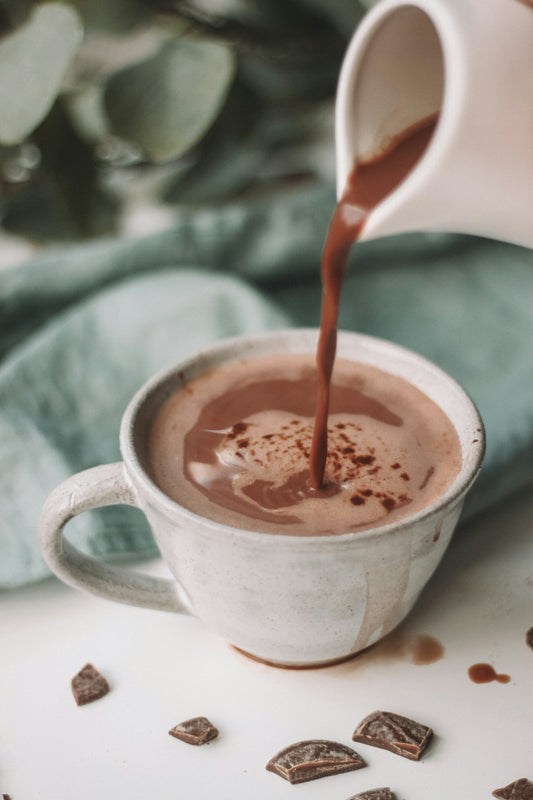 A warm mug of hot chocolate on a linen tablecloth, surrounded by soft light and stillness. A quiet morning ritual.
